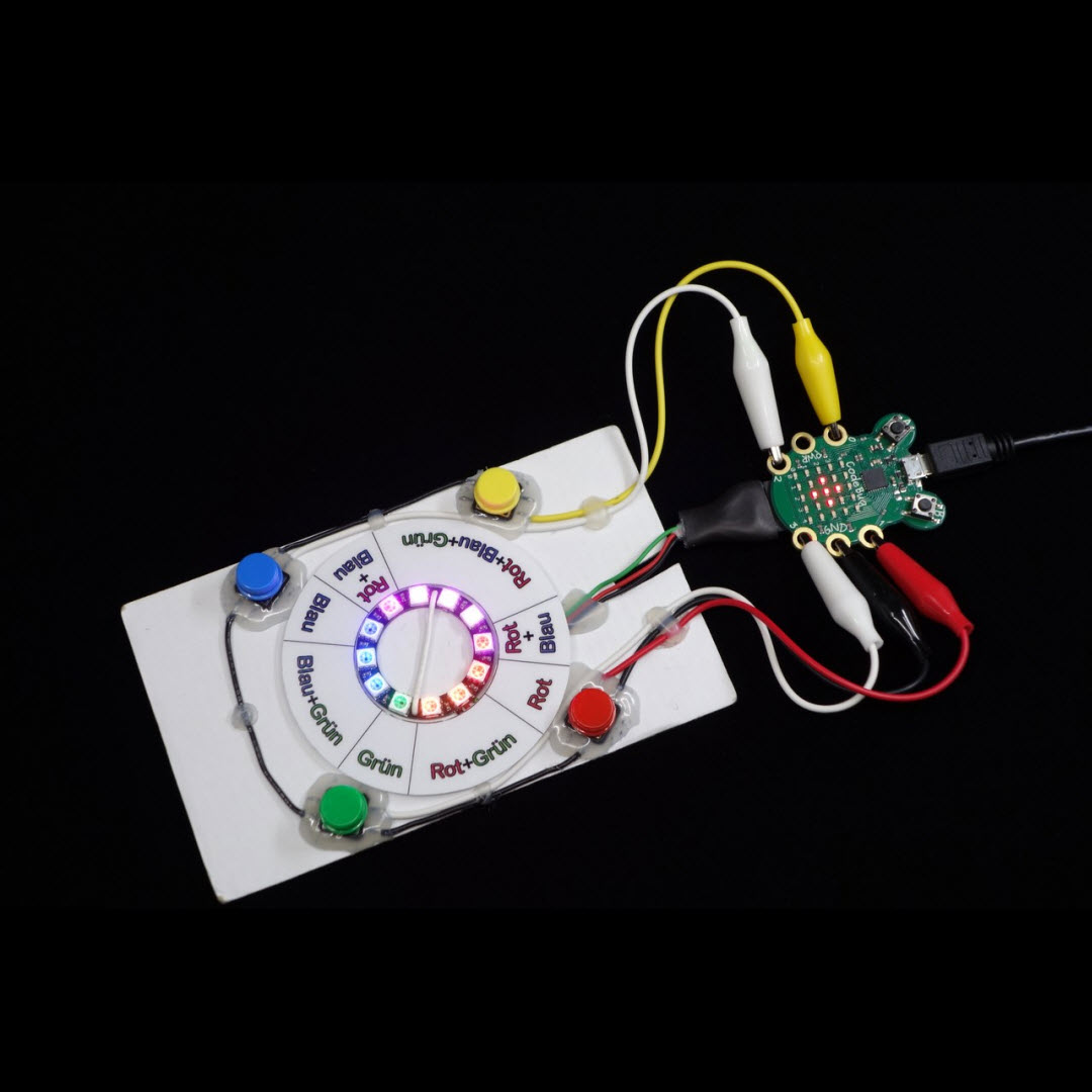 Foto: Leuchtscheibe-mini bestehend aus LED-Ring auf Karton mit vier farbigen Tasten angeschlossen an die Sterueung CodeBug