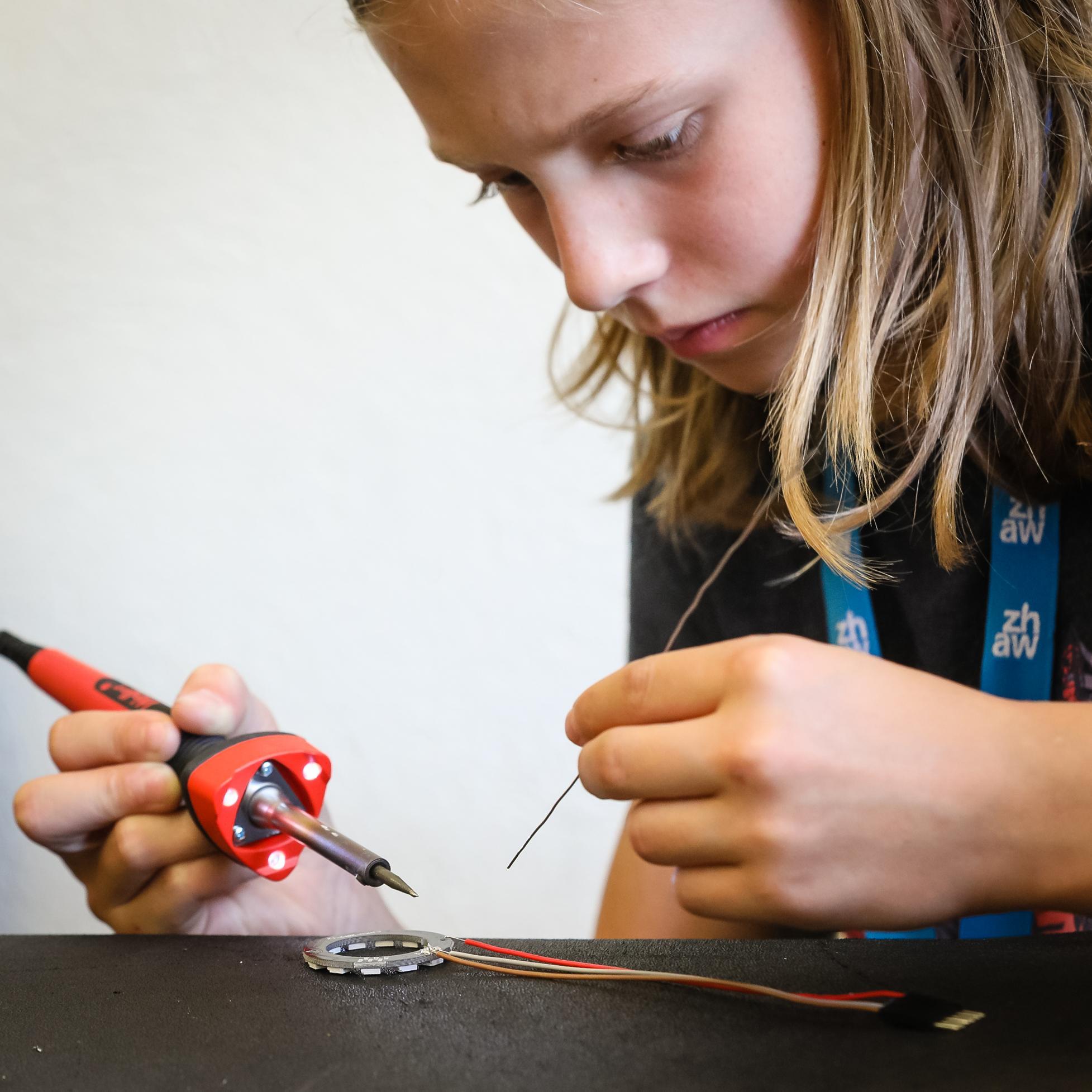 Foto von der Herstellen des LightBags: 
                        Mädchen lötet Kabel an LED-Ring